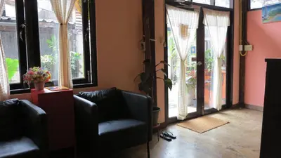a living room with two chairs and large windows at Non House Bangkok บ้านนอนโฮสเทล in Bangkok