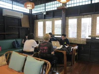 a group of people sitting at a table with laptops at Non House Bangkok บ้านนอนโฮสเทล in Bangkok