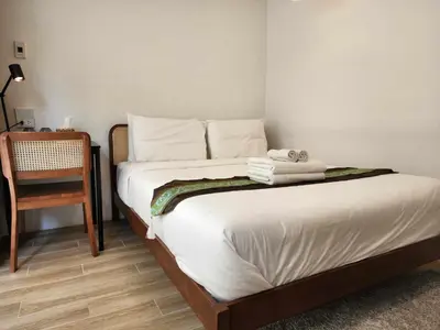a bedroom with a bed with white sheets and a chair at Lo-Ha Guest house, Contactless Check-in in Bangkok