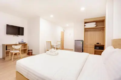 a bedroom with a white bed and a table and chairs at TAKKA Hotel - Bangna in Bangna