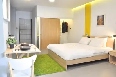 a bedroom with a large white bed and a table at A23 residence in Bangkok