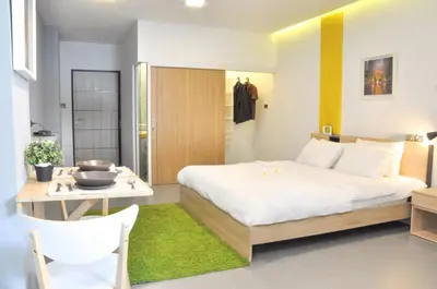 a bedroom with a large white bed and a table at A23 residence in Bangkok