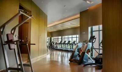 a gym with treadmills and ellipticals in a building at Chatrium Grand Bangkok in Bangkok