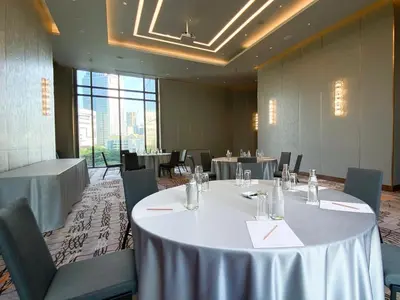 a conference room with tables and chairs and a large window at Chatrium Grand Bangkok in Bangkok