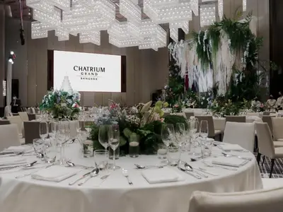 a table set up for a wedding with white tables and chairs at Chatrium Grand Bangkok in Bangkok