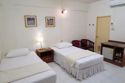 a hotel room with two beds and a desk at Phawana Sweet Hotel in Bangkok