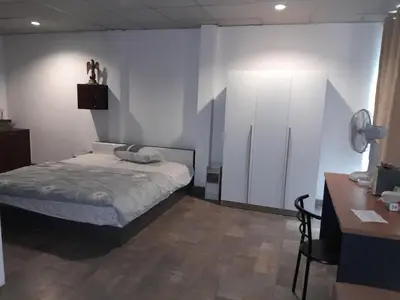 a bedroom with a bed and a cabinet and a desk at Flourish Apartments in Bangkok