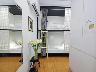 a room with white bunk beds and a vase of flowers at Ostay Asoke Bangkok in Makkasan