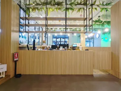 an office lobby with a large wooden reception desk at Ostay Asoke Bangkok in Makkasan