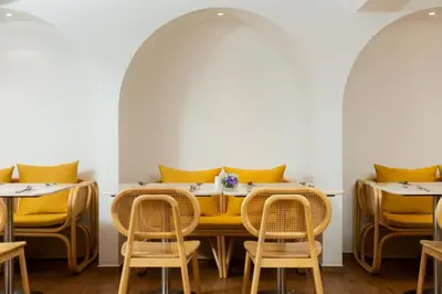 a dining room with yellow cushioned tables and chairs at Arck Hotel in Bangkok