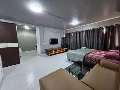 a room with a bed and a couch and a tv at ห้องพักรายวัน เมืองทองธานี เรือนศรีตรัง in Ban Bang Phang