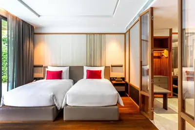 two beds in a hotel room with red pillows at Villa Deva Resort & Hotel Bangkok in Bangkok