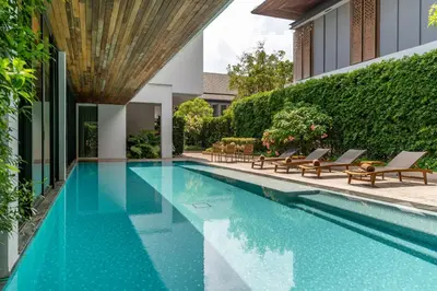 a swimming pool with lounge chairs next to a building at Villa Deva Resort & Hotel Bangkok in Bangkok