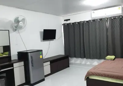 a bedroom with a bed and a tv and a bed and curtains at ห้องใหญ่-ห้องพักรายวัน เมืองทองธานี เรือนศรีตรัง in Nonthaburi
