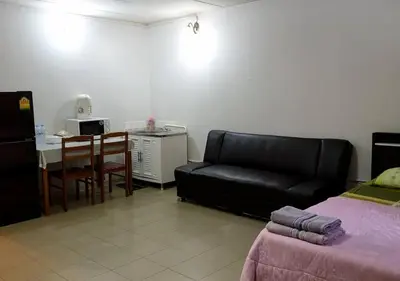 a living room with a black leather couch and a table at ห้องใหญ่-ห้องพักรายวัน เมืองทองธานี เรือนศรีตรัง in Nonthaburi
