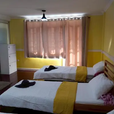 two beds in a room with a window at Aran Colonial House & Cafe Ngamwongwan in Ban Bang Khen (1)