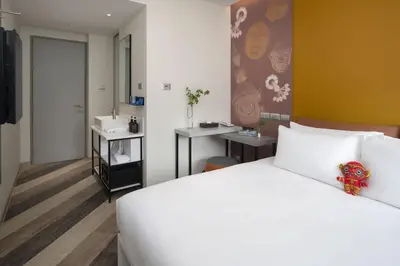 a bedroom with a white bed and a bathroom at Jono Bangkok Asok Hotel in Bangkok