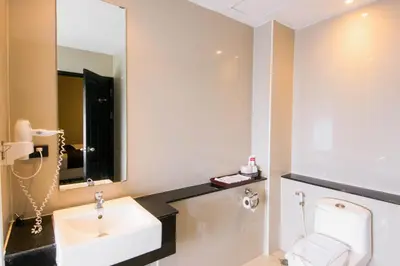 a bathroom with a sink and a toilet and a mirror at C Hotel Bangna in Bangkok