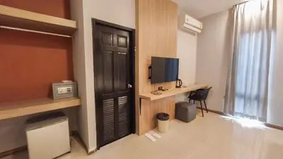 a room with a door and a desk with a television at C Hotel Bangna in Bangkok
