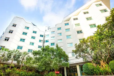 a large white building with trees in front of it at Graceland Bangkok by Grace Hotel - SHA Extra Plus in Bangkok