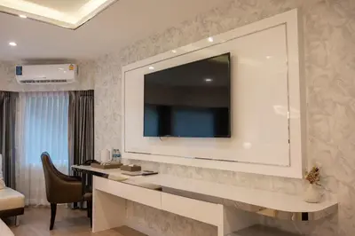 a hotel room with a desk and a television on a wall at Masa Hotel فندق الماسة شارع العرب in Bangkok