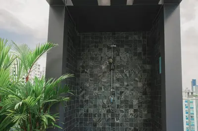 a bathroom with a shower with a stone wall at VOQUE Hotel & Serviced Residence Sukhumvit 51 in Bangkok