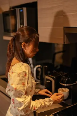 a woman standing in a kitchen preparing food at VOQUE Hotel & Serviced Residence Sukhumvit 51 in Bangkok