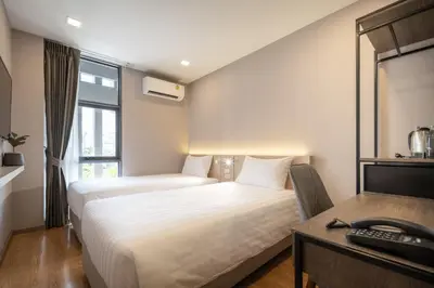 a hotel room with two beds and a desk at fyn park hotel in Makkasan