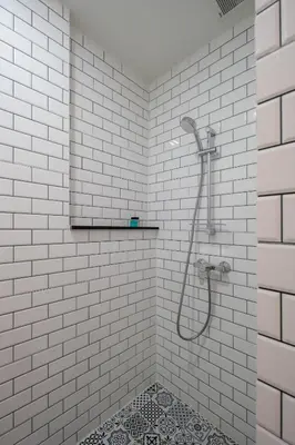 a white tiled bathroom with a shower and a tile floor at fyn park hotel in Makkasan