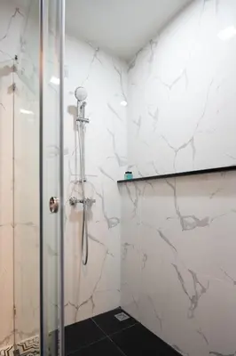 a shower in a bathroom with white marble walls at fyn park hotel in Makkasan
