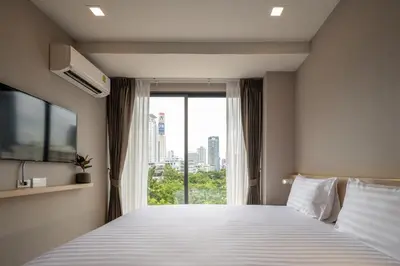 a bedroom with a large bed with a large window at fyn park hotel in Makkasan