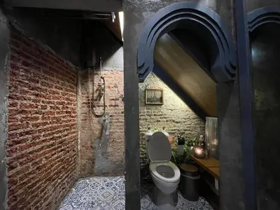 a bathroom with a toilet and a brick wall at Central Old Town Cottage in Bangkok