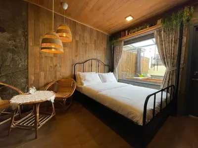 a bedroom with a bed and a table and a window at Central Old Town Cottage in Bangkok