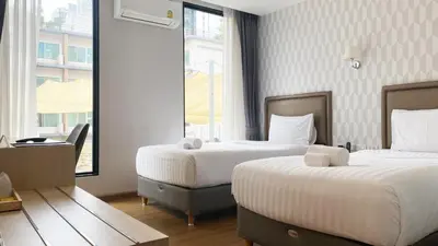 a hotel room with two beds and a window at Lucky Hotel Bangkok in Bangkok