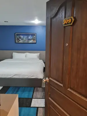a bedroom with a bed and a wooden door at Poonsuk Place Hotel in Bangkok Noi