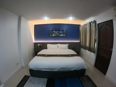 a bedroom with a large bed with a blue wall at Poonsuk Place Hotel in Bangkok Noi
