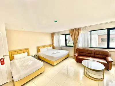 a hotel room with two beds and a couch at ABCYQ Hotel in Bangkok