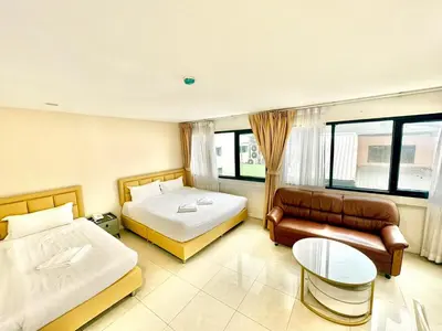 a hotel room with two beds and a couch at ABCYQ Hotel in Bangkok
