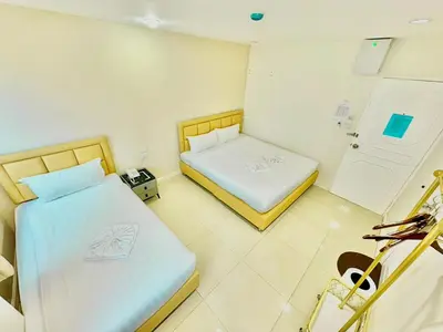a small room with two beds and a refrigerator at ABCYQ Hotel in Bangkok
