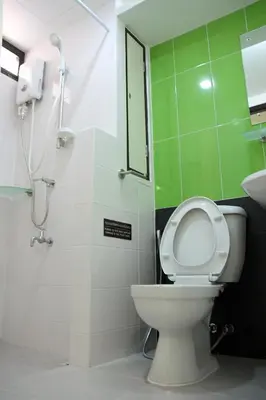 a bathroom with a toilet and a green wall at Peaberry Place - พีเบอร์รี่เพลส in Ban Zong Katiam
