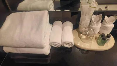 a bathroom with towels on a counter and a sink at Sukhothai Hotel and Residence Ratchada in Bangkok