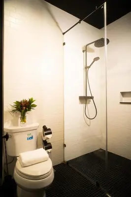 a bathroom with a shower with a toilet and a glass door at Baan Tuk Din Hotel in Bangkok
