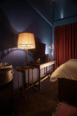 a bedroom with a bed and a table with a lamp at Baan Tuk Din Hotel in Bangkok