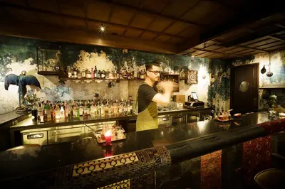 a man standing at a bar preparing a drink at Baan Tuk Din Hotel in Bangkok