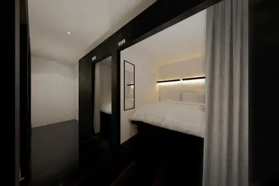 a small bedroom with a bed and a mirror at Forgotten Hostel Silom in Bang Rak