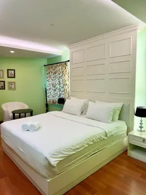 a bedroom with a large white bed with two towels on it at Sabai Dee Minitel in Dusit