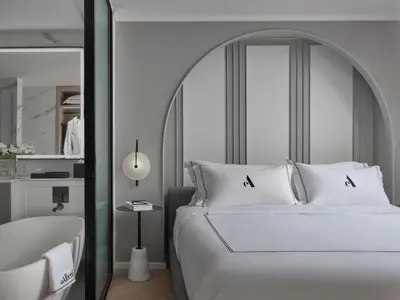 a bedroom with a large white bed and a tub at The Alberti Hotel - Sukhumvit 31 in Bangkok