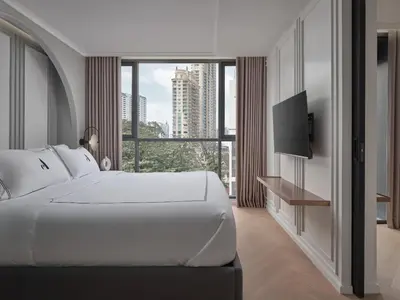 a bedroom with a large white bed and a large window at The Alberti Hotel - Sukhumvit 31 in Bangkok