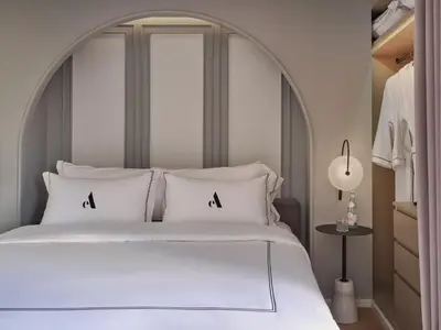 a bedroom with a large white bed with an arch headboard at The Alberti Hotel - Sukhumvit 31 in Bangkok