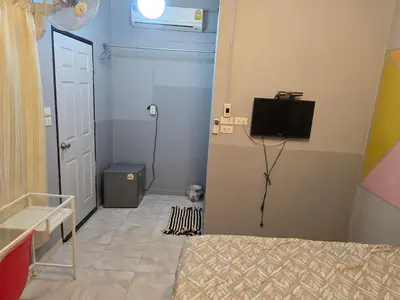 a bedroom with a bed and a television and a door at BEN HOUSE in Bangkok